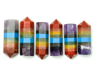 May include: Six multi-colored crystal wands with pointed tips. Each wand is layered with seven different colors, including red, orange, yellow, green, blue, indigo, and violet. The wands are arranged in a row on a white background.