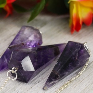 May include: Three amethyst crystal pendulums with silver chains. The crystals are faceted and have a deep purple color.
