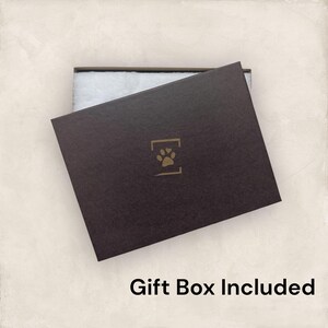 May include: A dark brown gift box with a paw print logo and the text "Gift Box Included". The box is partially open, revealing white padding inside. The box is on a light beige background.