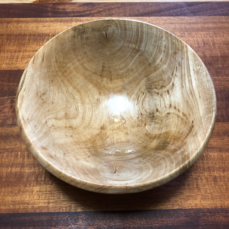 K&ouml;nnte beinhalten: Eine gro&szlig;e Holzsch&uuml;ssel mit hellbrauner Oberfl&auml;che. Die Sch&uuml;ssel hat eine glatte, polierte Oberfl&auml;che und ein nat&uuml;rliches Holzmaserungsmuster.