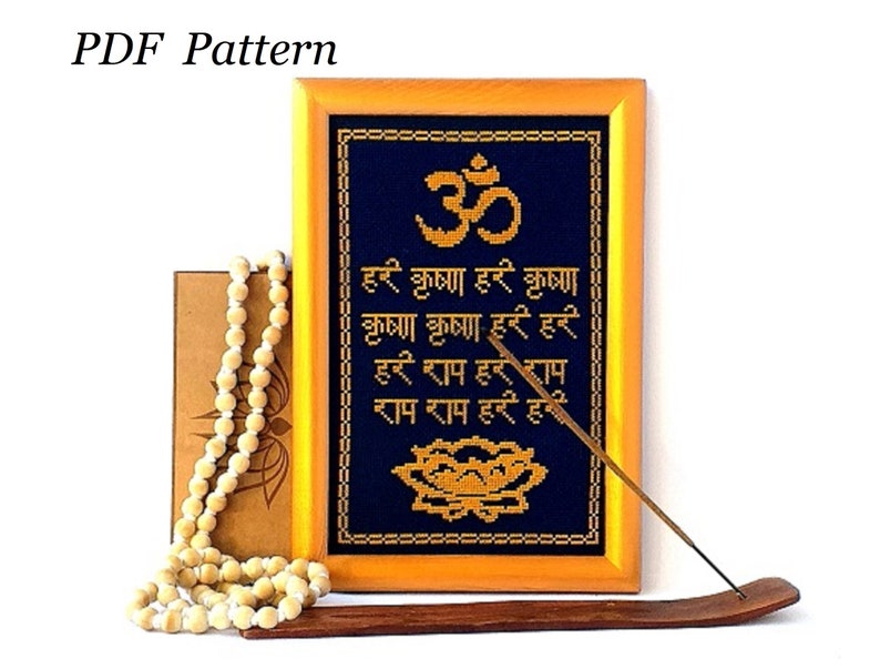 May include: A framed cross-stitch pattern featuring the Sanskrit word Om, a lotus flower, and a mantra in Hindi. The frame is made of wood and has a gold finish. The pattern is on a dark blue fabric with gold thread.