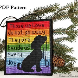 May include: A cross-stitch pattern for a rainbow-colored ornament featuring a black silhouette of a dog with the text "Those we love do not go away They are beside us every day".