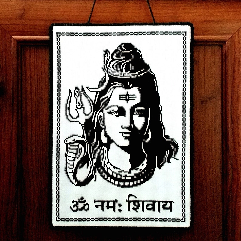 May include: Black and white embroidered wall hanging featuring a depiction of the Hindu deity Shiva with the text "Om Nam: Shivaya" at the bottom.