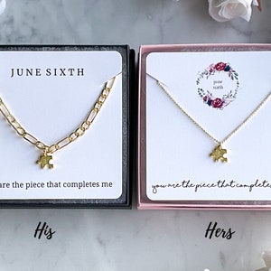 May include: Two gold necklaces with puzzle piece pendants in black and pink boxes. The necklaces are accompanied by cards that read "You are the piece that completes me." and "JUNE SIXTH".
