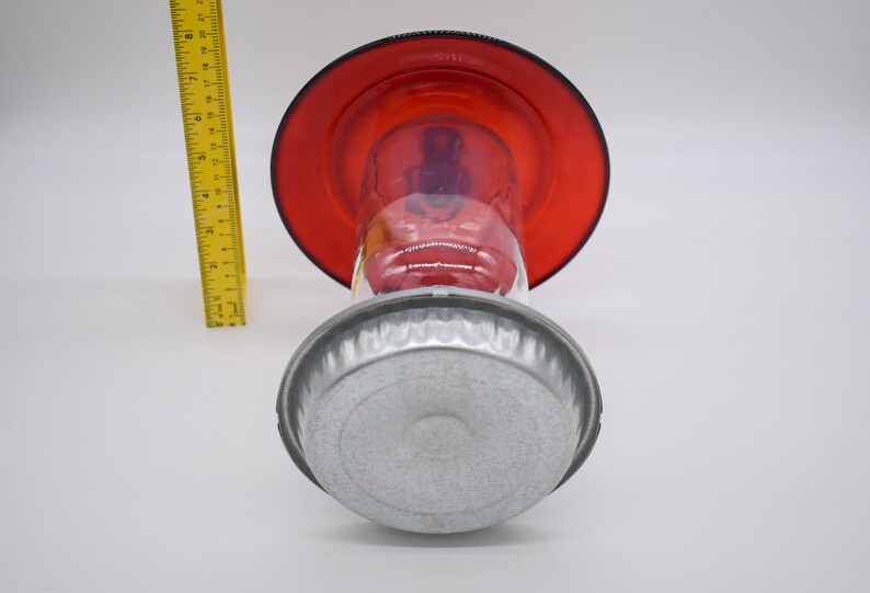 May include: A red glass hummingbird feeder with a metal base. The feeder has a clear glass reservoir and a red glass top.