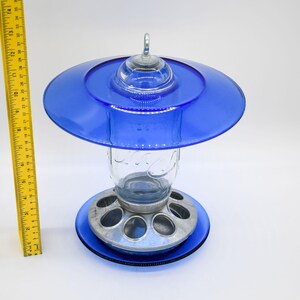 Front view of royal blue glass bird feeder with Mason jar and ruler for size reference