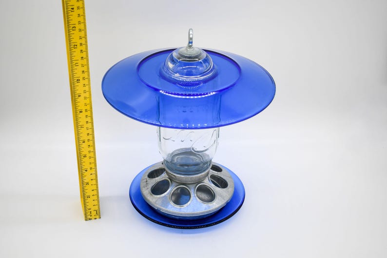 Front view of royal blue glass bird feeder with Mason jar and ruler for size reference