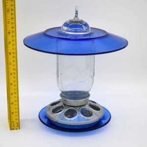 Royal blue glass bird feeder shown beside measuring ruler for height and size reference