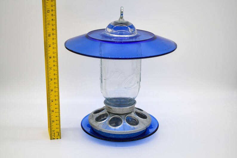 Royal blue glass bird feeder shown beside measuring ruler for height and size reference