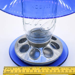 Close-up of royal blue glass bird feeder base and galvanized feeding ports with ruler