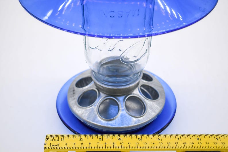 Close-up of royal blue glass bird feeder base and galvanized feeding ports with ruler