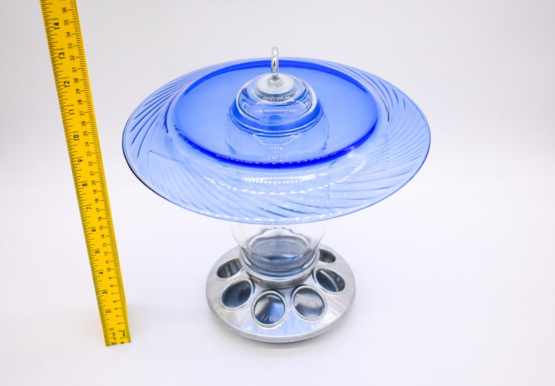 May include: A blue glass bird feeder with a clear glass reservoir and a silver metal base with multiple feeding ports.