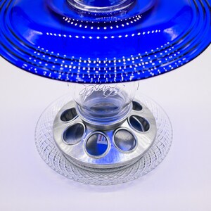 May include: A blue glass bird feeder with a clear glass jar and a metal base with six feeding ports.
