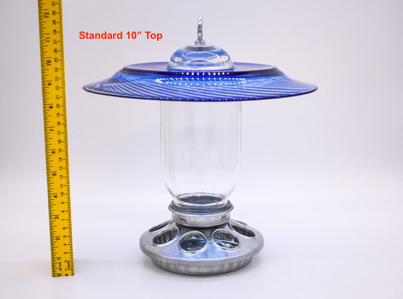 May include: A blue glass bird feeder with a 10-inch top and a clear glass jar. The feeder has a metal base with multiple feeding ports.