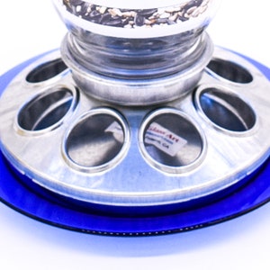 Close-up of galvanized metal bird feeder base showing circular mixed seed feeding ports