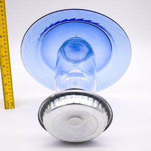 May include: A blue glass cake stand with a silver base. The stand has a swirl design on the top plate.
