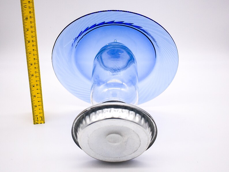 May include: A blue glass cake stand with a silver base. The stand has a swirl design on the top plate.