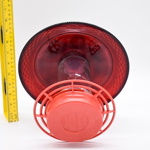 May include: Red glass hummingbird feeder with a red plastic base and a wire cage. The feeder has a decorative diamond pattern.