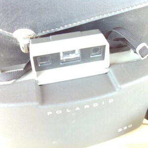 May include: A gray Polaroid camera with a black strap and the text "POLAROID 930" on the front.