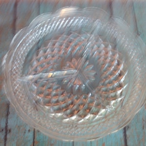 Puede incluir: Un plato de servir de vidrio transparente con tres secciones. El plato tiene un patrón de diamante y un borde festoneado.