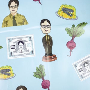 May include: A blue background with various stickers featuring a character from the TV show "The Office". The stickers include a cartoon of the character, a dollar bill with the character's face on it, a beetroot, and a bowl of yellow jelly with a stapler inside.