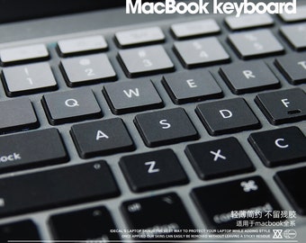 Może przedstawiać: Zbliżenie na czarną klawiaturę MacBooka z tekstem "MACBOOK 创意键盘贴 MacBook keyboard" nad nią. Klawiatura ma srebrną ramkę i czarne klawisze z białymi napisami. Tekst "轻薄简约不留残胶 适用于macbook全系 XX" jest widoczny na dole obrazu.