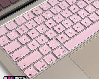 May include: Pink keyboard stickers for a Macbook. The stickers cover the keys and have a pink color scheme. The text "scanace (sticker) MACBOOK SKIN" is at the top of the image.