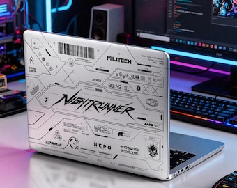 Könnte beinhalten: Ein silberner Laptop-Aufkleber mit einem detaillierten schwarz-weißen technischen Grafikdesign. Der Druck enthält den Text NIGHTRUNNER, MILITECH, MAXTAC, NCPD und ARASAKA sowie verschiedene Barcodes, Digitaluhr-Symbole und geometrische Muster.