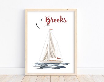 May include: A framed watercolor painting of a sailboat with a red sail and a red flag. The sailboat is on a blue body of water with three black birds flying above. The text "Brooks" is written in red cursive at the top of the painting.