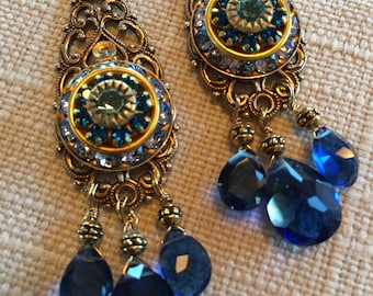 Könnte beinhalten: Goldene Filigranohänger mit einem blauen und goldenen Zentrum und drei baumelnden blauen Tropfenkristallen.