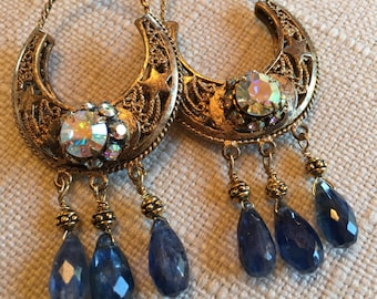 Könnte beinhalten: Ohrringe in Goldton mit einem Halbmond-Design, verziert mit schillernden Strasssteinen und baumelnden blauen Tropfen-Steinen.