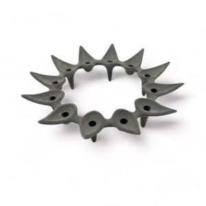 Könnte beinhalten: Ein dunkelgrauer, kreisförmiger Kerzenhalter mit einem Sonnenstrahl-Design. Der Metall-Kerzenhalter hat 12 Kerzenhalter und wird von kleinen, spitzen Füßen angehoben. Das Design weist blattförmige Elemente auf und eignet sich für die Inneneinrichtung.