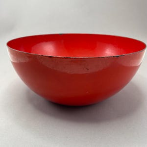 Puede incluir: Un tazón redondo de color rojo brillante con un acabado brillante. El tazón está hecho de metal y tiene un ligero borde alrededor del borde.