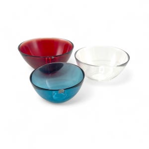 May include: Three glass bowls, one red, one blue, and one clear. The bowls are all the same size and shape, and they are arranged in a row.