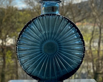 May include: A round, blue glass vase with a sunburst design. The vase is made by Finncrystal and says "Made in Finland" on the bottom.