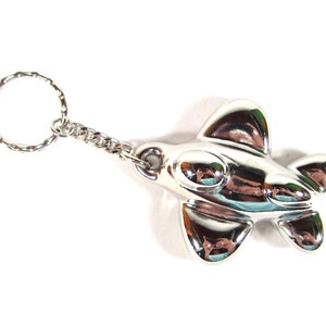 May include: A silver airplane keychain with a twisted metal ring. The airplane is detailed with a rounded nose and two small windows.
