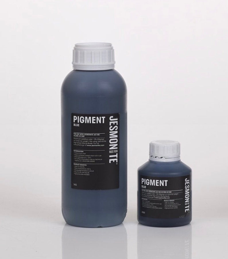 K&ouml;nnte beinhalten: Zwei Flaschen mit blauem Pigment, eine gro&szlig;e und eine kleine, beide mit der Aufschrift "Pigment Blau" und dem Markennamen "Jesmonite" auf der Seite. Die Flaschen sind aus dunkelblauem Glas und haben wei&szlig;e Deckel.