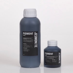 K&ouml;nnte beinhalten: Zwei Flaschen mit schwarzem Pigment, eine gro&szlig;e und eine kleine, beide mit der Aufschrift "Pigment Schwarz" und "Jesmonite Made in UK".