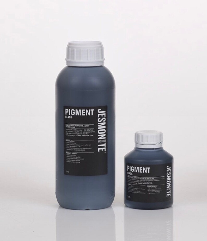 K&ouml;nnte beinhalten: Zwei Flaschen mit schwarzem Pigment, eine gro&szlig;e und eine kleine, beide mit der Aufschrift "Pigment Schwarz" und "Jesmonite Made in UK".