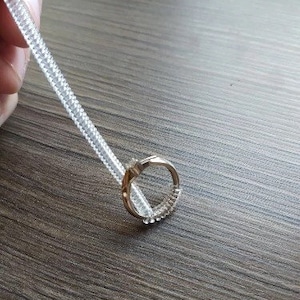May include: A close-up of a silver ring with a clear plastic ring around it. The ring is on a wooden surface.