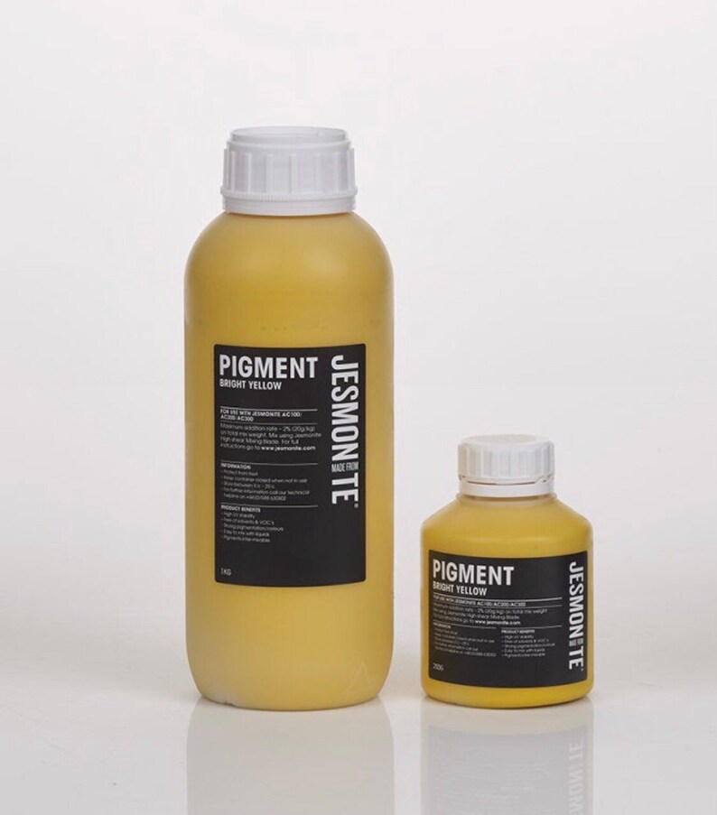 K&ouml;nnte beinhalten: Zwei Flaschen Jesmonite-Pigment in leuchtendem Gelb. Die gr&ouml;&szlig;ere Flasche ist 500 ml und die kleinere Flasche ist 250 ml. Beide Flaschen haben einen wei&szlig;en Verschluss und ein schwarzes Etikett mit dem Text "Pigment Leuchtendes Gelb" und "Jesmonite Hergestellt aus"