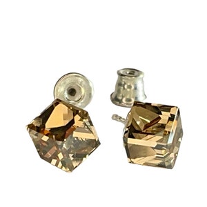 May include: A pair of square-cut, faceted, brown crystal stud earrings with silver posts and backs. The earrings are displayed on a white background, showcasing their geometric design and light-catching facets. These earrings are a classic jewelry accessory.