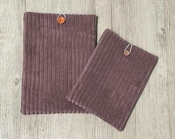 Peut inclure: Deux articles en tissu de velours côtelé de couleur violet clair. Le plus grand est rectangulaire, le plus petit est en biais. Chacun a une fermeture à bouton avec une boucle. Ce sont probablement des housses ou des étuis.