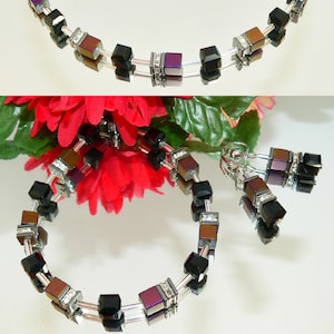 May include: A set of jewelry featuring a necklace, bracelet, and earrings. The jewelry is made of silver-toned metal and features black and purple square-shaped beads with clear rhinestones.