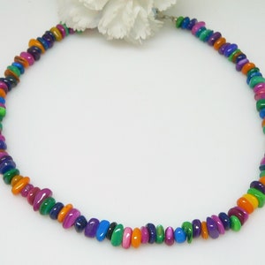 Könnte beinhalten: Eine bunte Halskette aus kleinen, flachen, mehrfarbigen Perlen. Die Perlen sind in einem sich wiederholenden Muster aus Grün, Orange, Lila und Blau angeordnet.