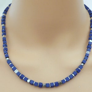 Könnte beinhalten: Eine Halskette aus dunkelblauen und silbernen quadratischen Perlen.