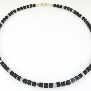 May include: A black and silver necklace with square beads. The necklace is made of black onyx and silver.