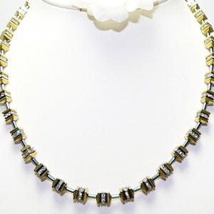 May include: A gold and silver necklace with a geometric design. The necklace is made of small, square-shaped links that are set with clear crystals.