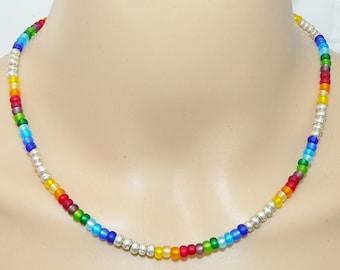 May include: A rainbow colored beaded necklace with silver beads interspersed throughout. The necklace is made of small, round beads in shades of red, orange, yellow, green, blue, indigo, and violet.