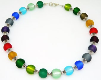 May include: A rainbow colored glass bead necklace with silver metal clasps and beads. The necklace is made of round beads in shades of green, blue, purple, red, orange, and yellow.